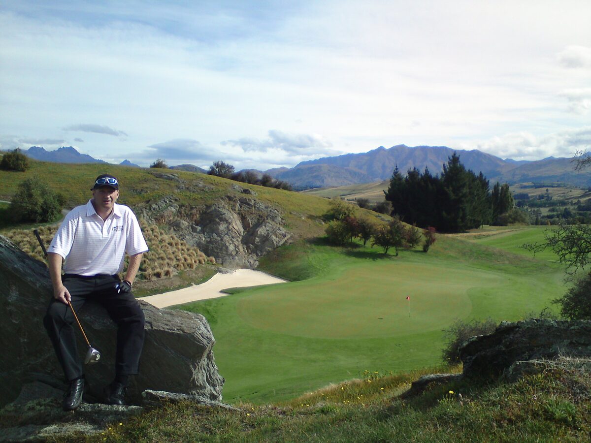 The 17th hole at The Hills Golf Course with bunker green and Remarkables mountains Queenstown New Zealand